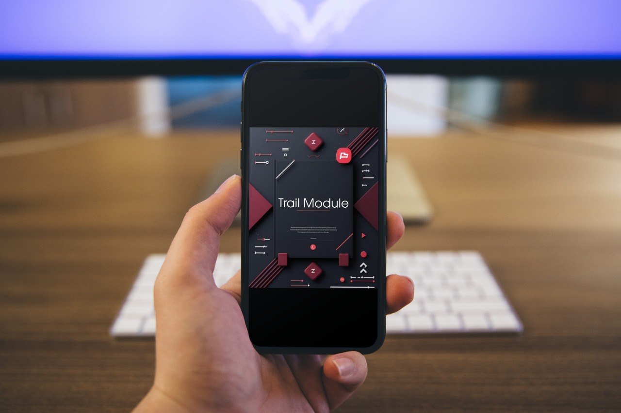 Hand holding a smartphone with a music app interface on a blurred desk background